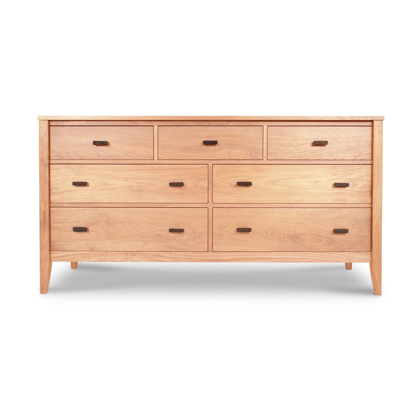 An eco-friendly Andover Modern 7-Drawer Dresser with seven drawers and round handles, featuring a natural cherry finish and angled legs, isolated on a white background. (Maple Corner Woodworks)